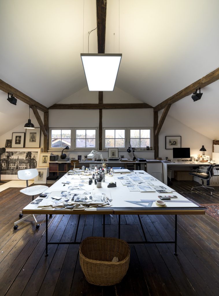 LED Pendelleuchte im modernen Atelier mit großem Arbeitstisch und Holzbalken-Decke