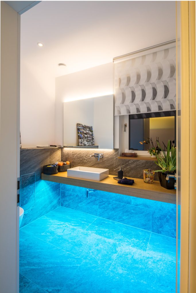 Badezimmer mit moderner LED Spiegelbeleuchtung und blauer Ambient Light Bodenbeleuchtung