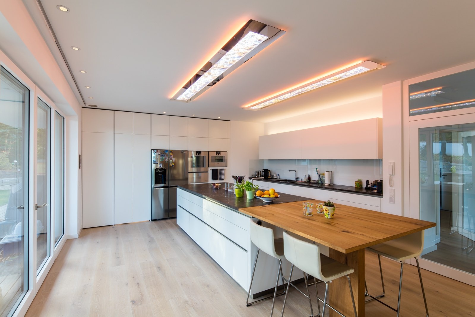 Küche mit Esstisch, direkter Beleuchtung und warmem Licht an der Decke